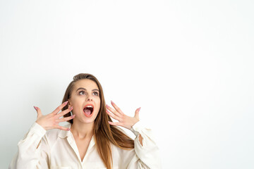 Shocked young caucasian woman with open mouth looking up and expresses surprise isolated over white background. Beautiful surprised brunette woman in studio