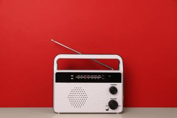 Retro radio receiver on table against red background - obrazy, fototapety, plakaty