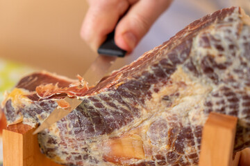 Man cuts mini ham with a special knife.