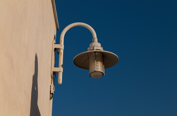 Street lamp on white wall against sky
