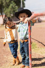 Two children in cowboy clothes on an outdoor ranch