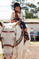 Fototapeta na wymiar Cowboygirl wearing helmet riding a white horse in a riding school