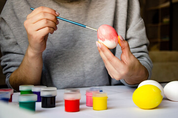 girl paints an egg for the holiday at Easter. girl draws with a brush on a chicken egg
