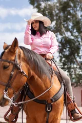 Foto op Canvas Cowgirl wearing boots and hat riding a horse outdoors © ERNESTO