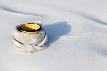Obraz na płótnie Canvas Warm drink in winter. Cup with drink coffee or tea wrapped in woolen scarf on white snow background