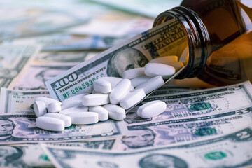 The tablets are scattered from the glass packaging on the banknotes. The concept is to raise the price of medicines. Investing in pharmaceuticals.