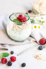 A glass with layered yogurt, chia seeds, oats and berries, served for breakfast