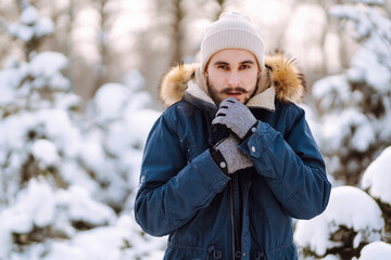 Portrait of  young man  in snowy winter forest. Season, christmas, travel and people concept.
