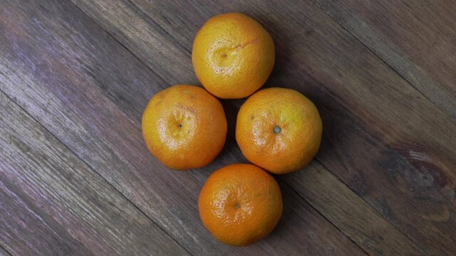 Close up view of slowly rotating ripe orange mandarins fruit isolation on wood background.