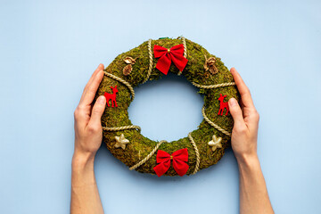 Woman hands holding Christmas wreath with fir tree, top view