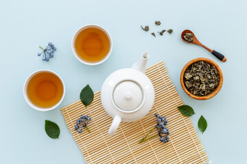 Tea drinking with white teapot and two cups with green leaves, top view