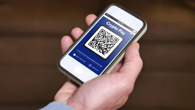 A man shows his cryptocurrency wallet address QR code, ready for a payment.	
