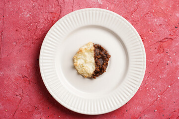 Several coconut flakes cookies dipped in chocolate on a white plate on magenta surface, top view