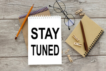 stay tuned. open notebook with text on wood table