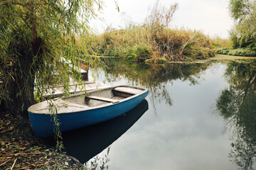 Naklejka na ściany i meble Light blue wooden boat on lake near pier, space for text