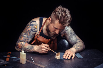 Craftsman working with leather cuts out leather goods in the tanner shop