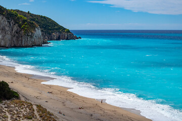 Fototapeta na wymiar Azure vibrant waves on coast of Lefkada island. Mylos sandy idyllic beach in Greece. Summer nature travel to Ionian Sea
