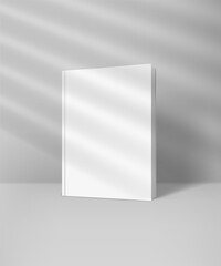 White book with blank hard cover mockup with sun flare effect. Light of the window with blinds