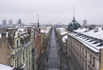 Aerial winter cityscape of Lodz, Poland.  View along the famous tourist attraction - Piotrkowska Street with rooftops covered in snow. © uslatar