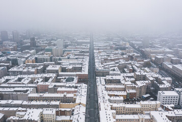 Aerial winter cityscape of Lodz, Poland.  View along the famous tourist attraction - Piotrkowska Street with rooftops covered in snow. © uslatar