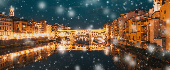 snowfall  over Florence Ponte Vecchio on river Arno at night, winter in Italy