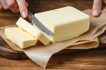 Cook cuts butter on the table with ingredients.
