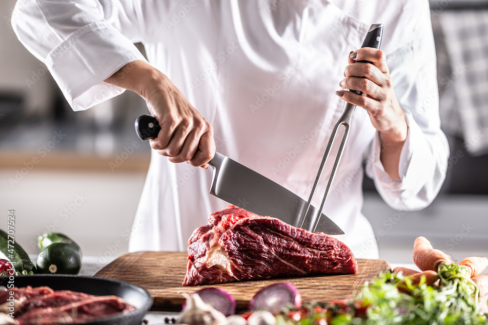 Wall mural professional cutlery used by a chef to cut red meat on a chopping board