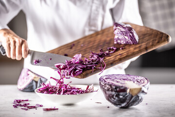 Chef cut half a raw red cabbage into pieces and puts them into a bowl