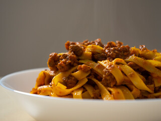 Traditional Italian pasta close-up. Plate of tagliatelle with meat sauce. Rustic Tagliatelle al...