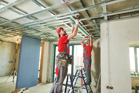 Gypsum plasterboard work. Drywall construction at home. Contractor worker installing metal frame on ceiling