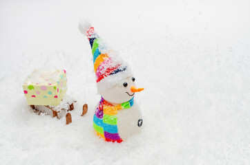 A snowman drives a gift on a wooden sled through the snow. LGBT concept