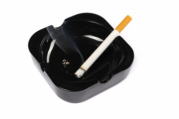 Lit cigarette in black ashtray isolated on white background