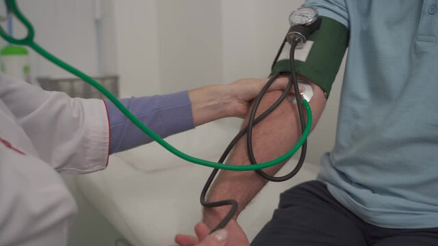 Medical and healthcare concept. Hypertension, high blood pressure and stroke precursors in middle age in men. Medical checkup. Female doctor in general practice measures pressure to patient in clinic.