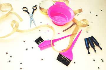 The composition of hairdressing tools on a beige background. Brushes, paints, hair balm, scissors, golden decor for home and salon treatments.