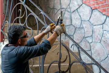 Man is holding welding machine in hands, preparing to start work on welding metal parts to stair...