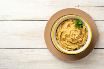Yellow pea puree or porridge or pudding in bowl on white wooden rustic background