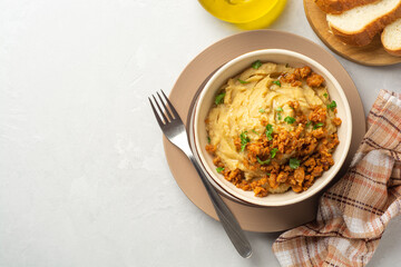 Yellow pea puree or porridge or pudding with meat sauce in bowl on concrete background