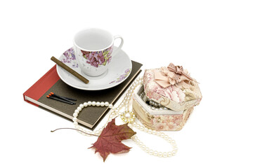 a round box with pearl beads and cup of tea on white background with copy space