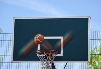 Basketball shield close - up outdoors . The ball flies into the basket .