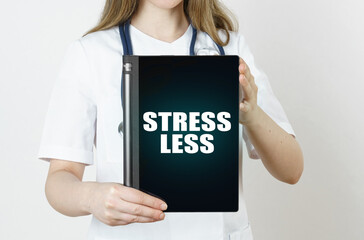 Fototapeta na wymiar The doctor is holding a tablet with the inscription - Stress Less