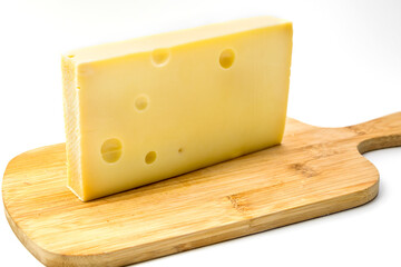 A piece of organic Emmental cheese with a knife on a wooden cutting board isolated over white background