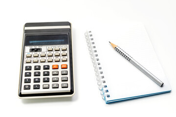 Calculator, pencil and notebook on white background. Close-up. Copy space