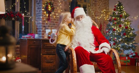 Fototapeta na wymiar What do you want. Santa Claus sitting at the armchair and listening wishes of little girl standing nearby. New Year and holidays concept