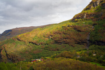 Landscape in Norway with mountains, waterfall and wooden houses