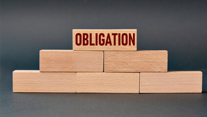 OBLIGATION - word on wooden blocks on dark background