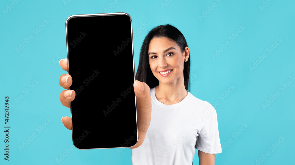 Wall mural Mobile App Mockup. Beautiful Young Woman Showing Big Smartphone With Black Screen