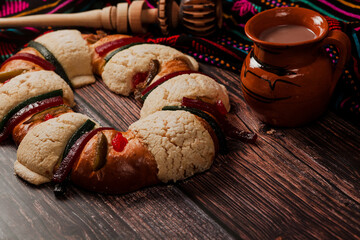 Rosca de reyes or Epiphany cake and clay mug of mexican hot chocolate on a wooden table in Mexico Latin America