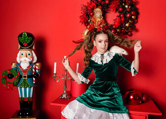 a girl in a green velvet dress sits near a nutcracker and a white rat on her shoulder