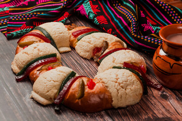 Rosca de reyes or Epiphany cake and clay mug of mexican hot chocolate on a wooden table in Mexico...