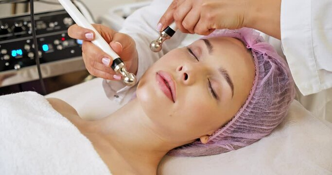Beautiful woman receiving facial microcurrent treatment at spa salon. Beautician using electrical impulses for facial procedures. Woman in spa salon. Woman in a spa salon on cosmetic procedures.